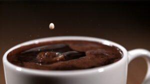 Slow motion close up cinemagraph shot of a drop of milk floating above cup of coffee.